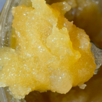 Close-up of a yellow, crystalline, waxy substance with a grainy texture inside a container.